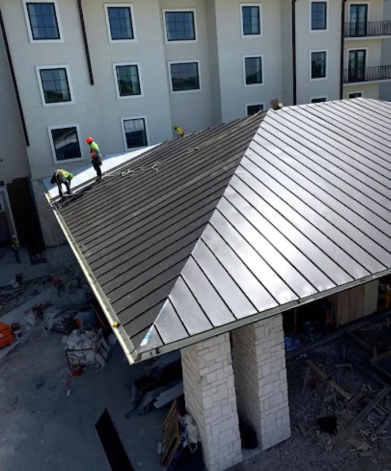 Crew installing standing seam metal roof panels on a commercial project in Denair